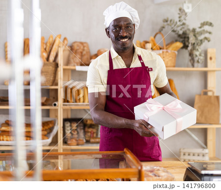 Portrait of male baker in apron with box Portrait of male baker in apron with box 141796800