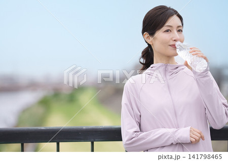 ウォーキング中にペットボトルの水を飲むミドル女性 ウォーキング中にペットボトルの水を飲むミドル女性 141798465