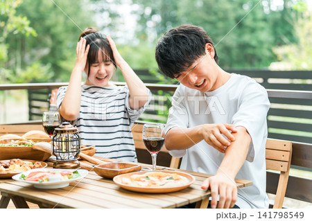 アウトドアで食事中に虫刺されで困っているカップル アウトドアで食事中に虫刺されで困っているカップル 141798549