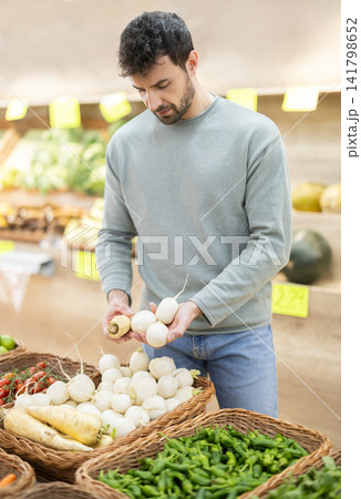 Male buyer chooses ripe turnip for purchase in greengrocer shop Male buyer chooses ripe turnip for purchase in greengrocer shop 141798652