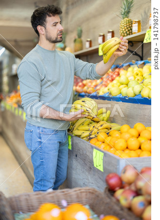 Adult man choosing bananas at vegetable shop 141798737
