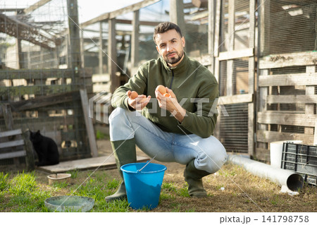 Positive man stands and holds in hands palms few fresh chicken eggs Positive man stands and holds in hands palms few fresh chicken eggs 141798758