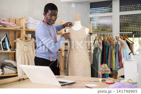 African man seamstress communicates with customer via video call work with mannequin African man seamstress communicates with customer via video call work with mannequin 141798905