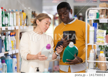 African man and European woman spouses buyer scan QR code on packaging of liquid detergent in shop African man and European woman spouses buyer scan QR code on packaging of liquid detergent in shop 141798913