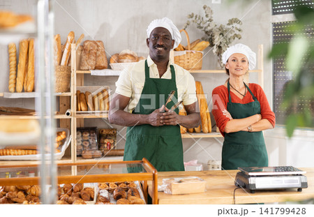 Cheerful man and woman bakers in bakehouse Cheerful man and woman bakers in bakehouse 141799428