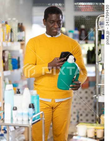 Before making purchase, African man buyer scan QR code on packaging of liquid detergent Before making purchase, African man buyer scan QR code on packaging of liquid detergent 141799430