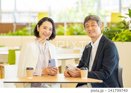 カフェでスマホを見ながら会話するシニア夫婦 カフェでスマホを見ながら会話するシニア夫婦 141799740