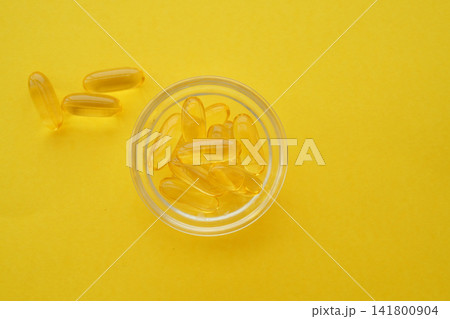 fish oil capsules in a bowl on a bright yellow background fish oil capsules in a bowl on a bright yellow background 141800904