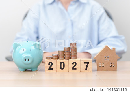 Happy New Year 2027 with house model and Coins stack. real estate, Home loan, tax, investment, mortgage, financial, savings and New Year Resolution concepts 141801116