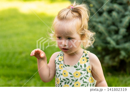Serious Toddler Girl Raising One Hand Outdoors Serious Toddler Girl Raising One Hand Outdoors 141802319