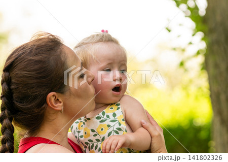 Mother Kissing Toddler Daughter on Cheek Outdoors Mother Kissing Toddler Daughter on Cheek Outdoors 141802326