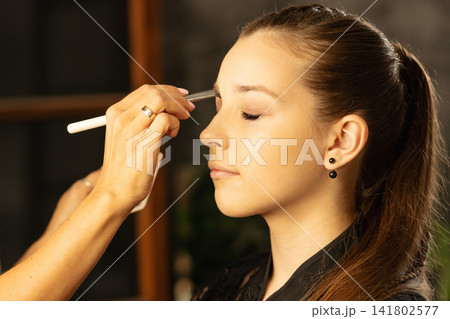 Makeup Artist Detailing Teen Client Eyelid With Brush In Salon Makeup Artist Detailing Teen Client Eyelid With Brush In Salon 141802577