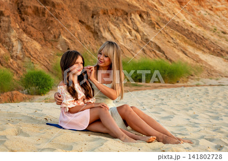 Mother Adjusting Daughter Sun Hat In Sandy Landscape 141802728