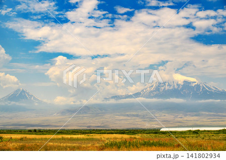 Vast open field with distant snowy Ararat peaks under dramatic sky Vast open field with distant snowy Ararat peaks under dramatic sky 141802934