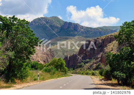 Scenic road cutting through rugged mountainous terrain with dense greenery Scenic road cutting through rugged mountainous terrain with dense greenery 141802976