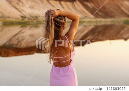 Blonde Woman Arranging Hair Beside Rocky Quarry Lake Blonde Woman Arranging Hair Beside Rocky Quarry Lake 141803035