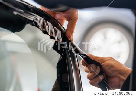 A car wrapping specialist applies a polyurethane film to the car. Detailer PPF A car wrapping specialist applies a polyurethane film to the car. Detailer PPF 141803069