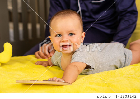 Smiling Baby During Tummy Time With Caregiver Nearby Smiling Baby During Tummy Time With Caregiver Nearby 141803142