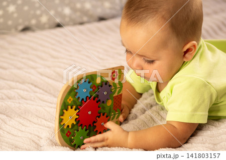Curious Baby Boy Explores Colorful Wooden Gear Puzzle Curious Baby Boy Explores Colorful Wooden Gear Puzzle 141803157