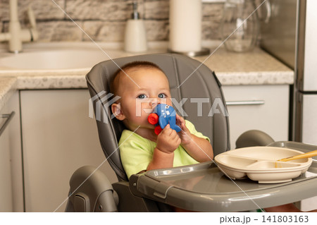 Baby Boy Bites Airplane Toy During Kitchen Mealtime Baby Boy Bites Airplane Toy During Kitchen Mealtime 141803163