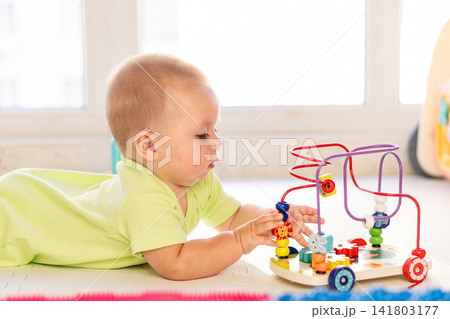 Infant Boy Practices Fine Motor Skills With Bead Maze Infant Boy Practices Fine Motor Skills With Bead Maze 141803177