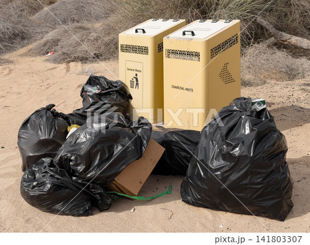 Scattered trash bags near public trash bins in a natural area. Human impact on the environment. Scattered trash bags near public trash bins in a natural area. Human impact on the environment. 141803307