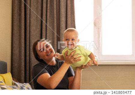 Baby Boy Touches Mother Chin During Playful Window Moment 141803477