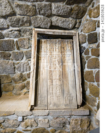 Weathered wooden door framed by rugged stone masonry Weathered wooden door framed by rugged stone masonry 141803628
