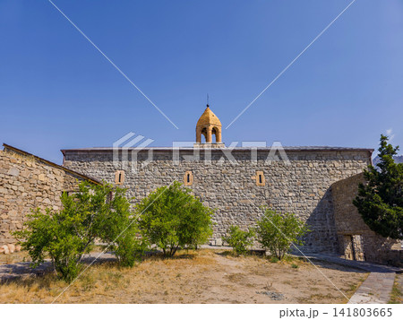 Ancient stone church with bell tower, surrounded by green trees Ancient stone church with bell tower, surrounded by green trees 141803665