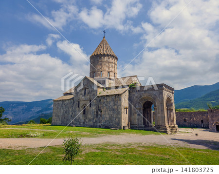 Historic Armenian Tatev monastery stands on grassy hillside near mountains Historic Armenian Tatev monastery stands on grassy hillside near mountains 141803725
