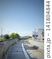 青空の下を流れる水量の少ない都市河川と住宅街 141804844