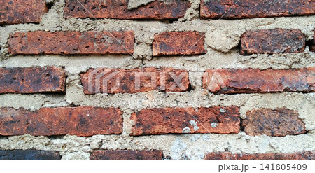 Dark red clay brick wall with a rough mortar texture. Dark red clay brick wall with a rough mortar texture. 141805409