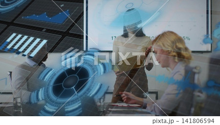 Presenting female leader in dress pointing toward wall display at conference room, holding tablet Presenting female leader in dress pointing toward wall display at conference room, holding tablet 141806594