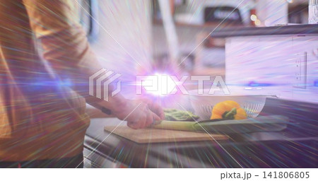 Chopping brown-shirted man slicing green veggies at kitchen counter with knife on board, copy space 141806805