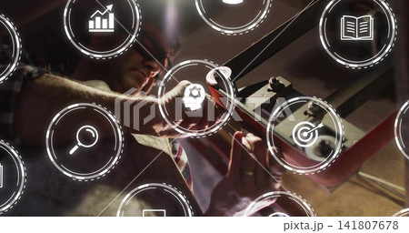Tightening mature technician wearing safety glasses using wrench at workshop machine, with AR icons Tightening mature technician wearing safety glasses using wrench at workshop machine, with AR icons 141807678