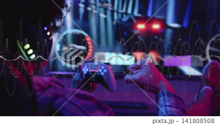 Playing man in plaid shirt holding wireless gamepad at desk with RGB screens, waveform, copy space Playing man in plaid shirt holding wireless gamepad at desk with RGB screens, waveform, copy space 141808508