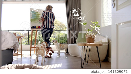 Painting woman artist wearing striped shirt and dark trousers in living room with easel, dogs, AR 141809071