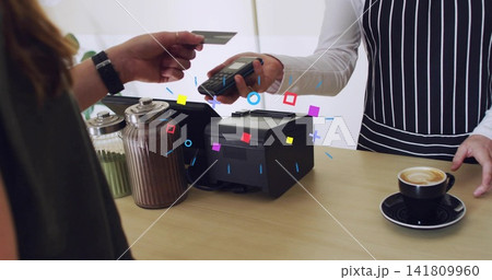 Handing customer extending credit card toward reader at cafe counter, aproned staff with printer Handing customer extending credit card toward reader at cafe counter, aproned staff with printer 141809960