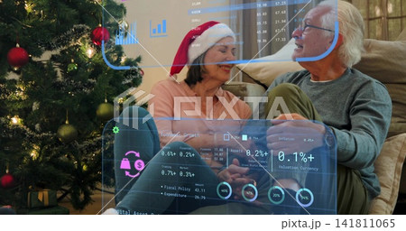 Sharing senior couple viewing AR overlays on couch at home, with Christmas tree, Santa hat 141811065