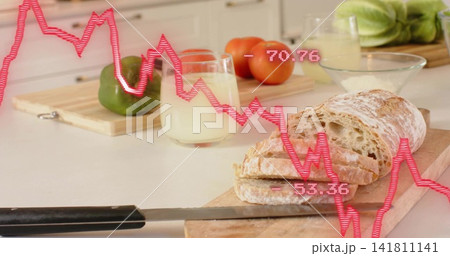 Slicing rustic loaf on wood board in home kitchen, with serrated black-handled knife and pink graph Slicing rustic loaf on wood board in home kitchen, with serrated black-handled knife and pink graph 141811141
