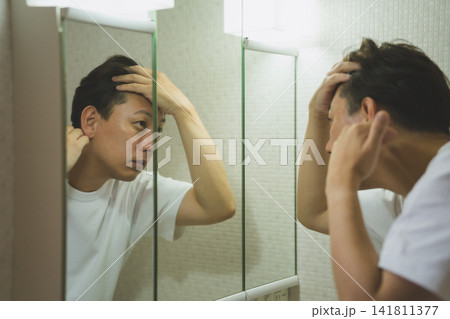 洗面台で薄毛を気にする40代男性のAGAチェック 洗面台で薄毛を気にする40代男性のAGAチェック 141811377