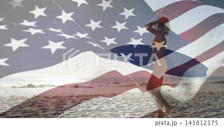Walking woman in bikini carrying longboard toward water on sand, American flag overlay, copy space Walking woman in bikini carrying longboard toward water on sand, American flag overlay, copy space 141812175