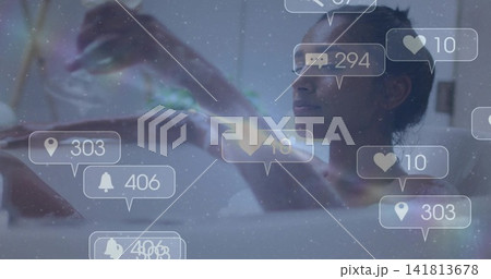 Holding phone, woman reclining in bathtub in bathroom, with social notifications floating nearby Holding phone, woman reclining in bathtub in bathroom, with social notifications floating nearby 141813678