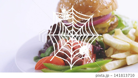 Showing sesame-seed hamburger on white plate at tabletop, with fries and salad, spiderweb overlay Showing sesame-seed hamburger on white plate at tabletop, with fries and salad, spiderweb overlay 141813710
