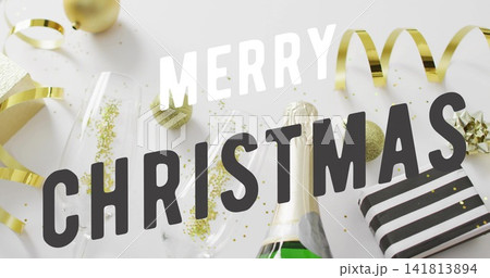 Displaying holiday flat-lay on white table, featuring MERRY CHRISTMAS overlay, flutes, gold baubles Displaying holiday flat-lay on white table, featuring MERRY CHRISTMAS overlay, flutes, gold baubles 141813894