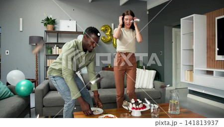 Cheering couple in green, beige clothes, at coffee table with cake and gold 3 balloon Cheering couple in green, beige clothes, at coffee table with cake and gold 3 balloon 141813937