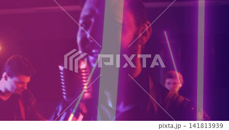 Singing lead vocalist leaning into vintage ribbon microphone on club stage, wearing leather jacket 141813939