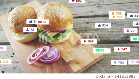 Showing pair of sesame cheeseburgers sitting on wood board, with red onion rings, social icons Showing pair of sesame cheeseburgers sitting on wood board, with red onion rings, social icons 141813985