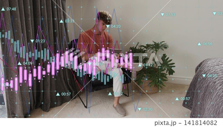 Sitting man wearing rust shirt white pants checking phone on chair in bedroom, stock charts 141814082