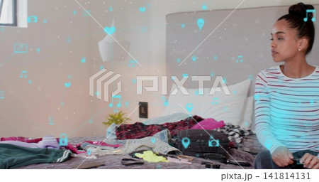 Sitting woman in striped top and dark pants packing suitcase in bedroom, AR icons, copy space 141814131